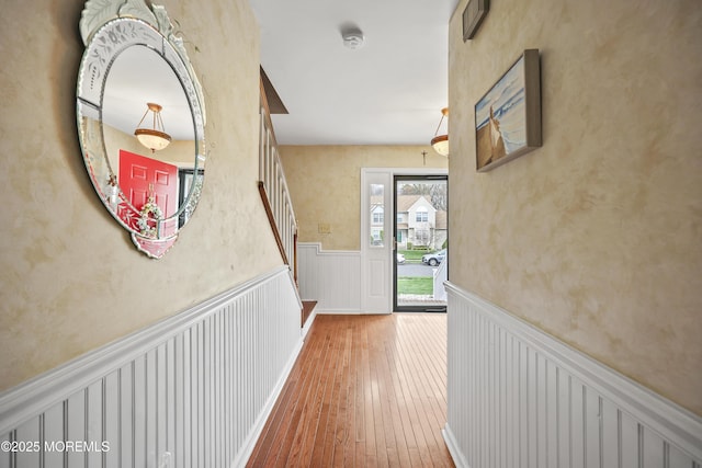 hall with stairs, a wainscoted wall, and hardwood / wood-style flooring