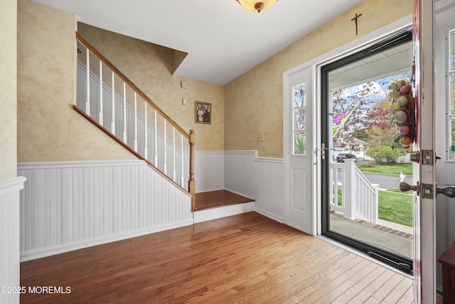 entrance foyer featuring hardwood / wood-style flooring, stairway, and a wainscoted wall