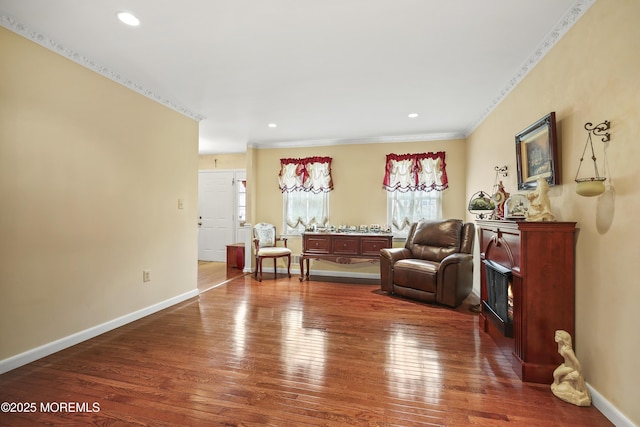 living area with wood-type flooring, baseboards, crown molding, and recessed lighting