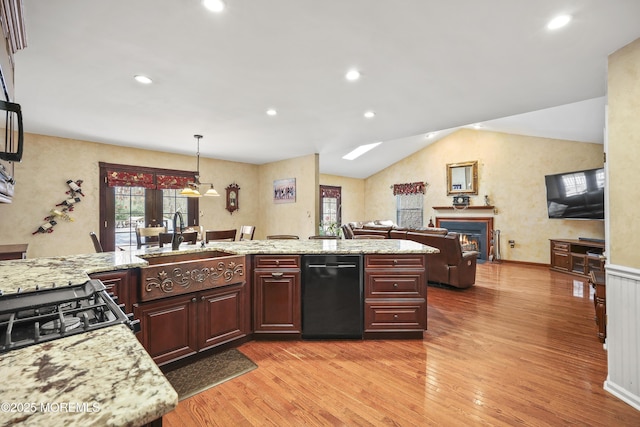 kitchen featuring a warm lit fireplace, light wood-style floors, a healthy amount of sunlight, and a sink