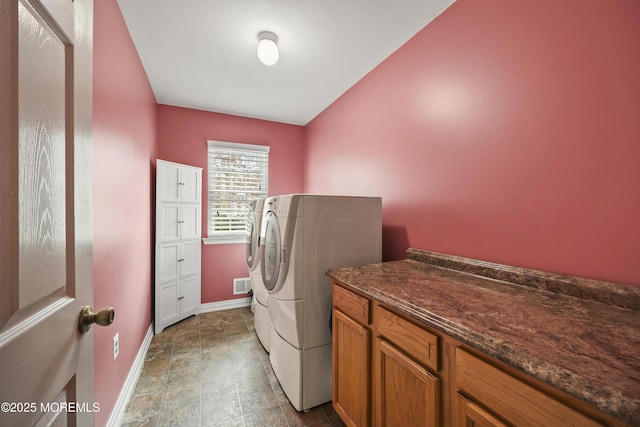 washroom with visible vents, baseboards, washer and clothes dryer, and cabinet space