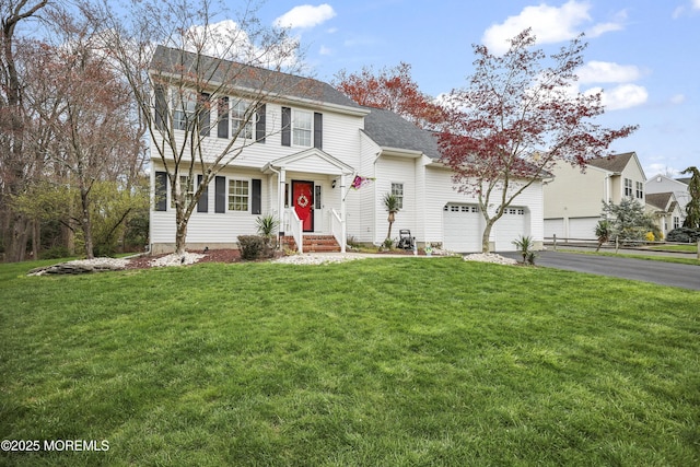 colonial house featuring a shingled roof, a front lawn, driveway, and a garage
