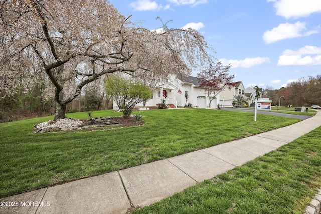 view of home's community with driveway, a yard, and a garage