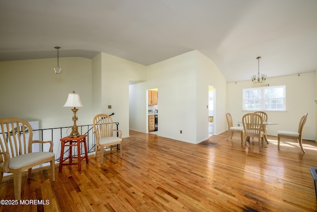 living area featuring a chandelier, light wood-style floors, and lofted ceiling