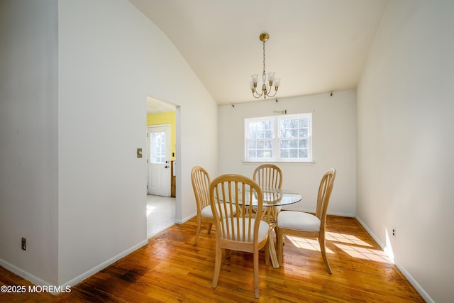 dining space featuring a notable chandelier, baseboards, vaulted ceiling, and wood finished floors