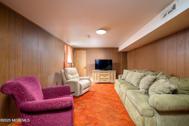 carpeted living area with wood walls and visible vents
