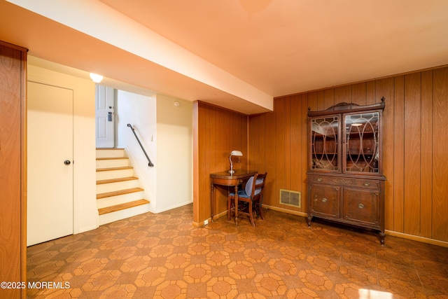 unfurnished office with wood walls, baseboards, and visible vents
