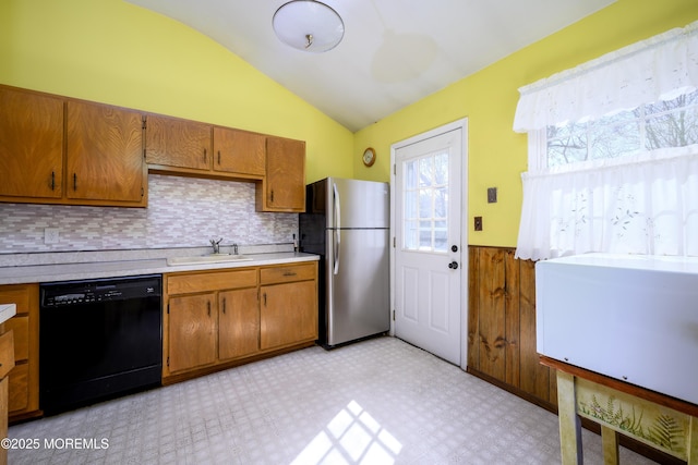 kitchen with freestanding refrigerator, light floors, black dishwasher, a sink, and wainscoting