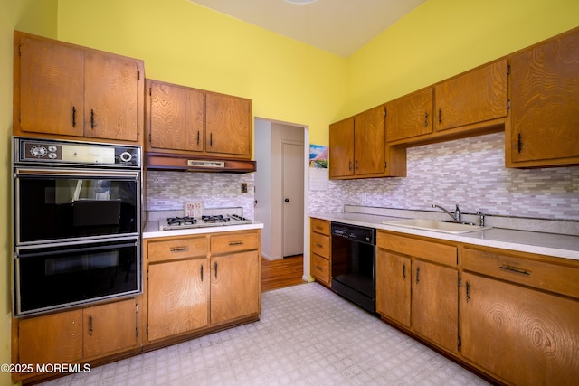 kitchen with tasteful backsplash, a sink, light countertops, black appliances, and light floors