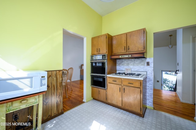 kitchen with light countertops, white appliances, light floors, and under cabinet range hood