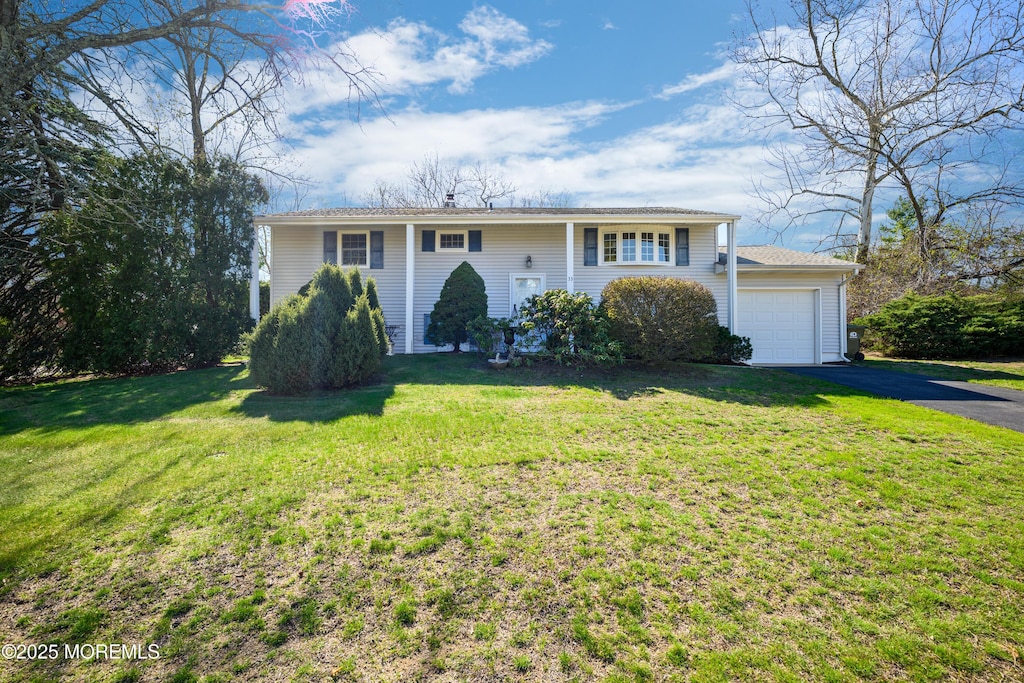 view of front of house featuring a garage, aphalt driveway, and a front lawn