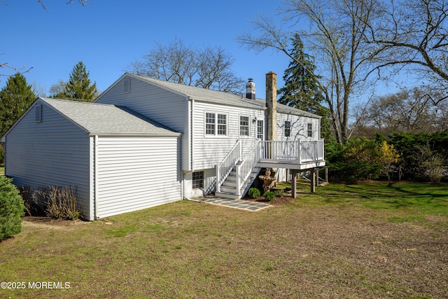 back of property with a deck, a lawn, a chimney, stairway, and roof with shingles