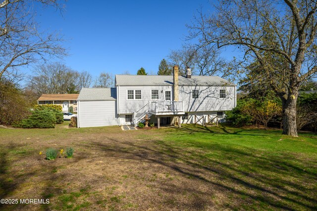 back of house with roof with shingles, a lawn, and a chimney