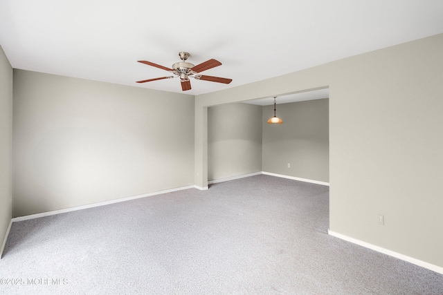 carpeted spare room featuring ceiling fan and baseboards