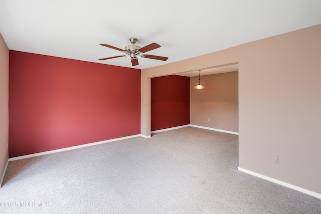 carpeted empty room with ceiling fan and baseboards