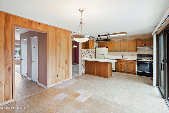 kitchen with electric range oven, light countertops, freestanding refrigerator, brown cabinets, and tasteful backsplash