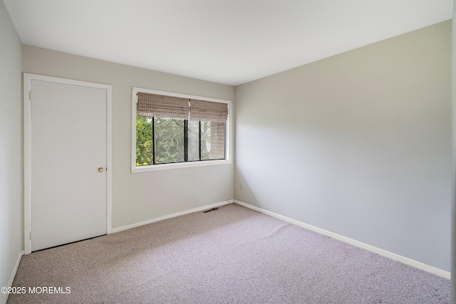 carpeted spare room featuring baseboards