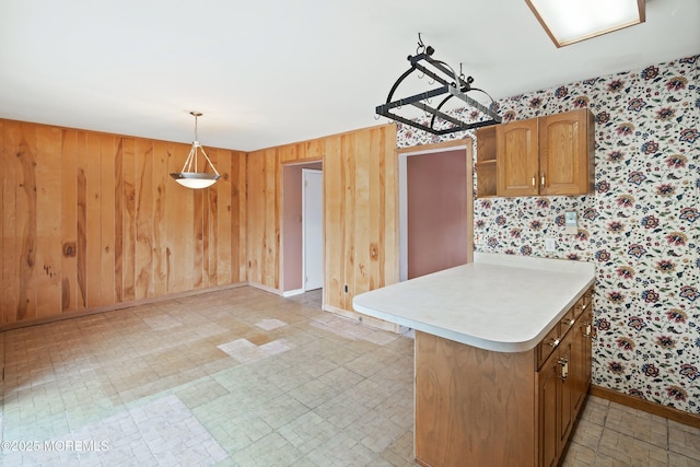 kitchen with wallpapered walls, light countertops, baseboards, decorative light fixtures, and a peninsula