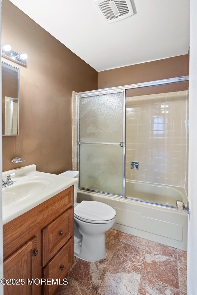 full bathroom featuring vanity, bath / shower combo with glass door, and toilet