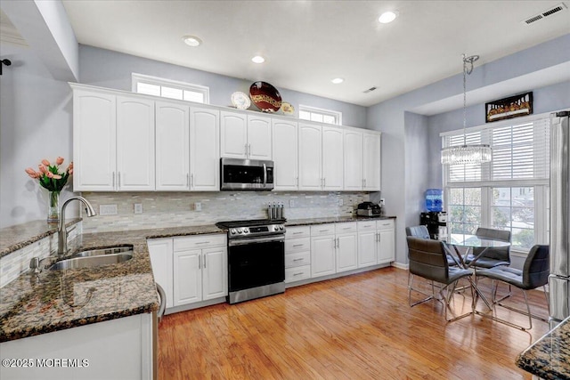 kitchen featuring dark stone counters, white cabinets, visible vents, appliances with stainless steel finishes, and a sink