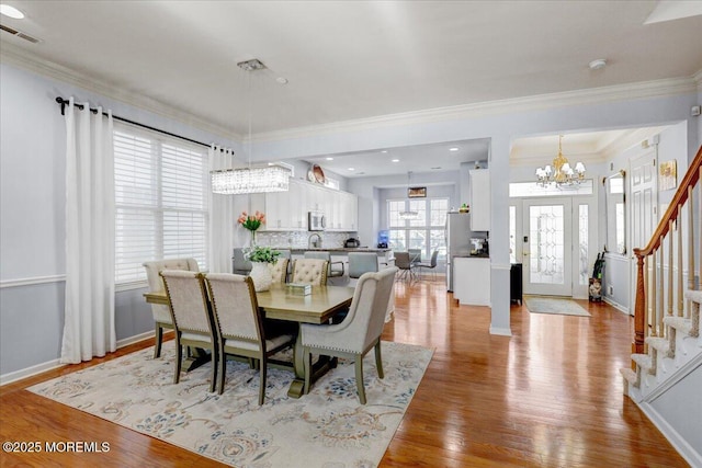 dining area with visible vents, a chandelier, crown molding, light wood finished floors, and stairs