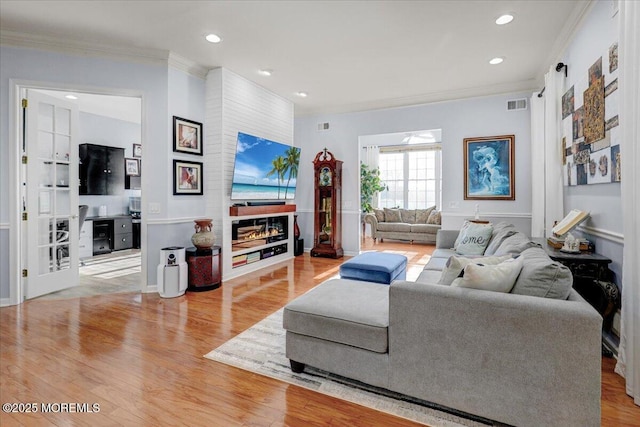 living area with crown molding, visible vents, recessed lighting, and wood finished floors
