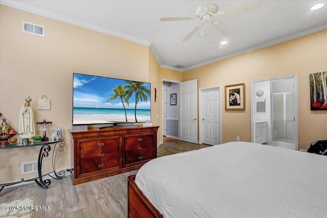 bedroom with ceiling fan, ensuite bath, ornamental molding, visible vents, and wood finished floors