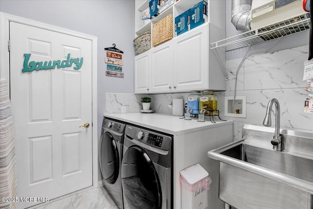laundry area with cabinet space, washing machine and clothes dryer, marble finish floor, and a sink