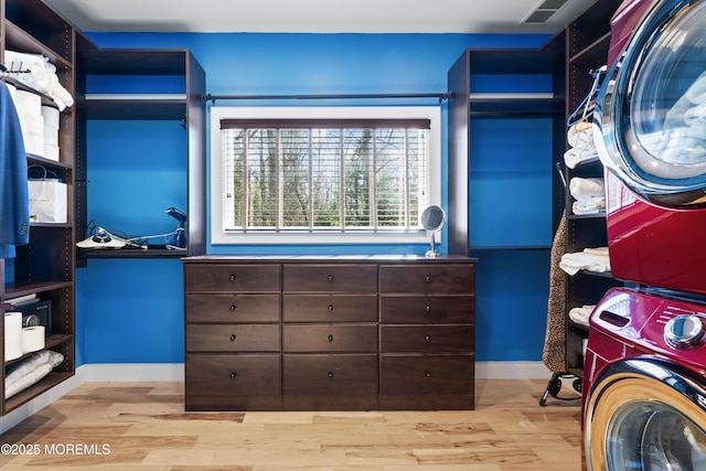 spacious closet with visible vents, stacked washer / drying machine, and wood finished floors