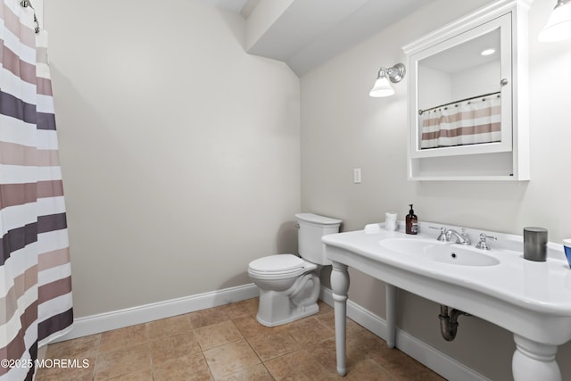 bathroom featuring curtained shower, baseboards, a sink, and toilet