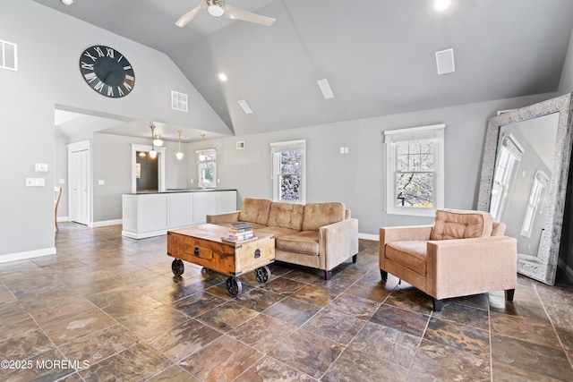 living area with ceiling fan, high vaulted ceiling, stone tile floors, visible vents, and baseboards
