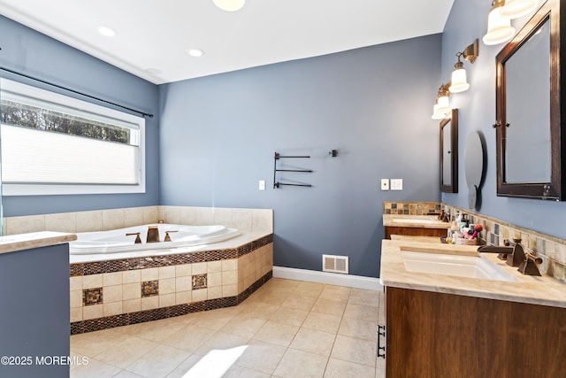 full bath with visible vents, a bath, a sink, double vanity, and tile patterned flooring