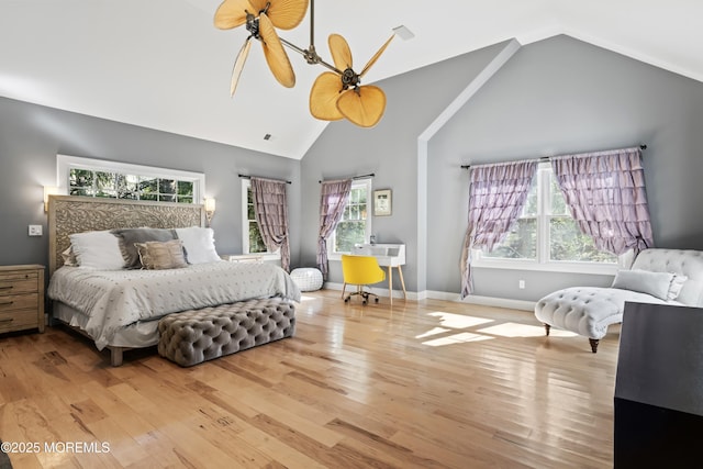 bedroom with wood finished floors, high vaulted ceiling, baseboards, and multiple windows