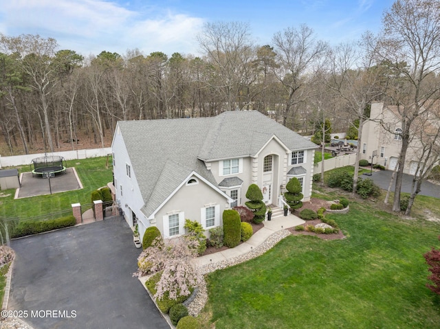 101 Erin Dr, Jackson, NJ 08527 - view of front of home with fence, a shingled roof, a front lawn, stucco siding, and a trampoline