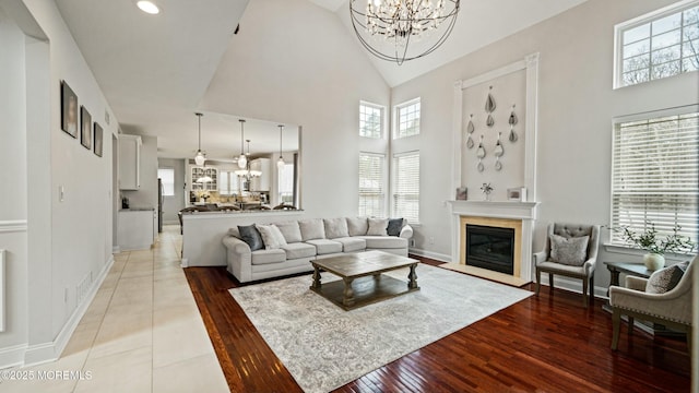 101 Erin Dr, Jackson, NJ 08527 - living area featuring a glass covered fireplace, baseboards, high vaulted ceiling, and a notable chandelier