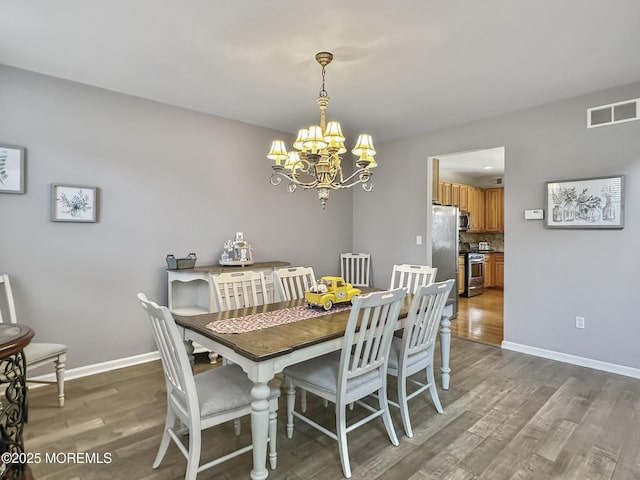 dining space with a chandelier, wood finished floors, baseboards, and visible vents