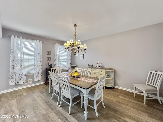 dining area with a chandelier, wood finished floors, baseboards, and visible vents