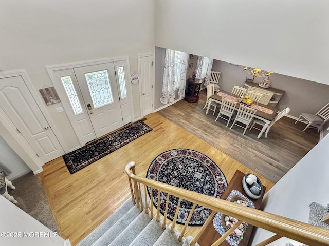foyer featuring wood finished floors, a high ceiling, baseboards, and stairway