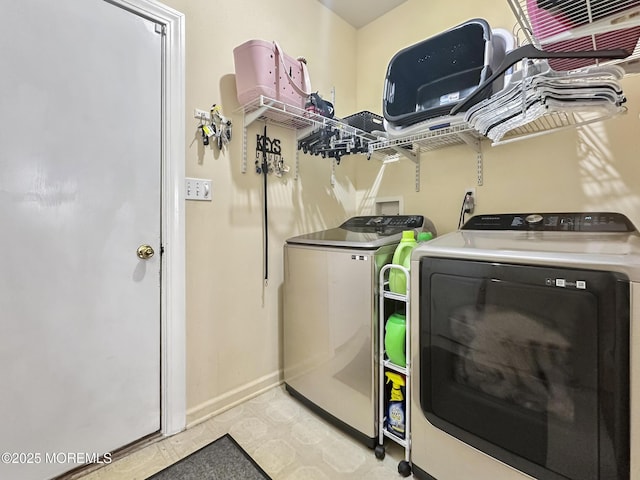 washroom featuring washer and dryer, laundry area, baseboards, and light floors
