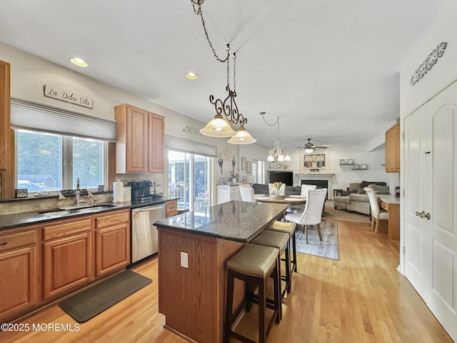 kitchen featuring a center island, a kitchen bar, ceiling fan, stainless steel dishwasher, and a sink