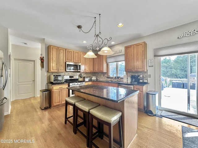 kitchen with decorative backsplash, a breakfast bar, a sink, and appliances with stainless steel finishes