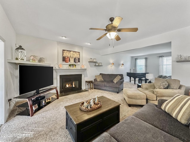 carpeted living area featuring a fireplace with flush hearth and ceiling fan