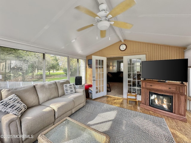 living area featuring french doors, ceiling fan, wood finished floors, and lofted ceiling with beams