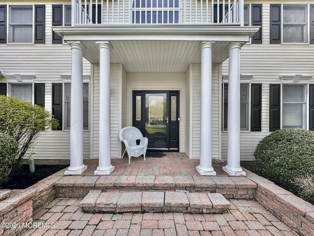 property entrance featuring covered porch and a balcony