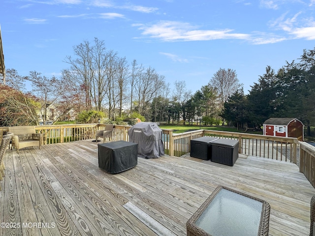 wooden deck featuring area for grilling, a storage unit, and an outdoor structure