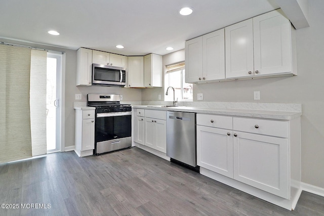 950 Bay Ave, Toms River, NJ 08753 - kitchen featuring stainless steel appliances, white cabinets, a sink, and wood finished floors