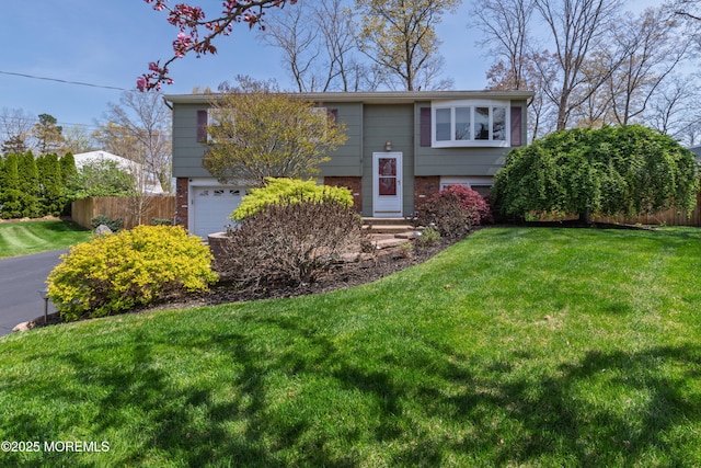 bi-level home featuring fence, an attached garage, a front lawn, and brick siding