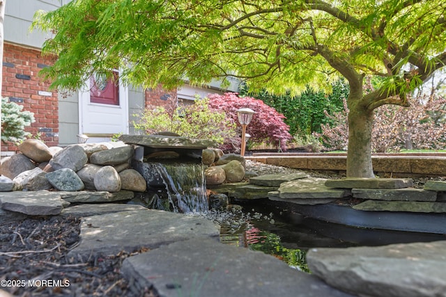exterior details featuring brick siding and a small pond