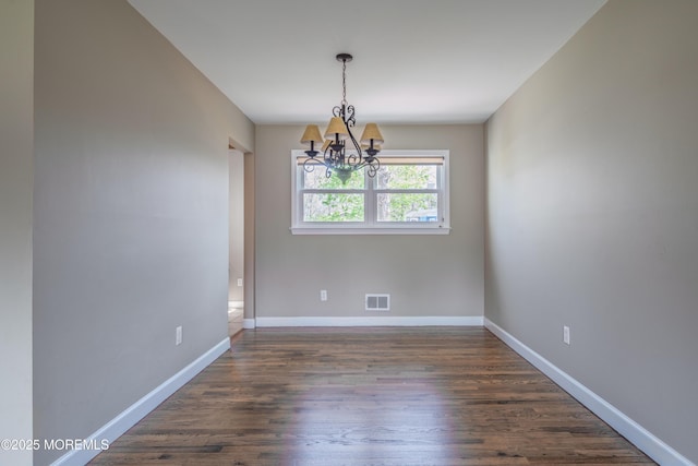 empty room featuring a chandelier, baseboards, visible vents, and dark wood-type flooring