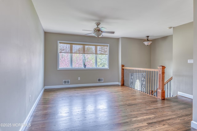 spare room with baseboards, a ceiling fan, wood finished floors, and visible vents